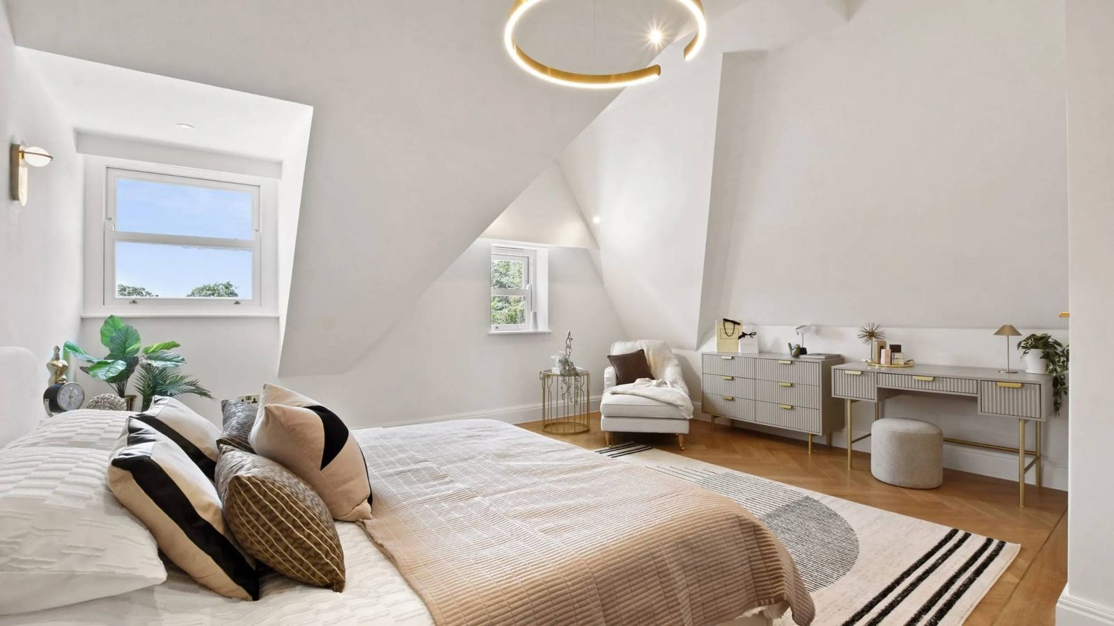 Staged loft bedroom with a ring pendant light, dressing table and reading chair